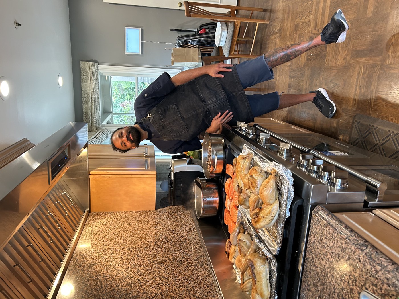 Chef Manny plating roasted chicken and seared salmon in a client's kitchen